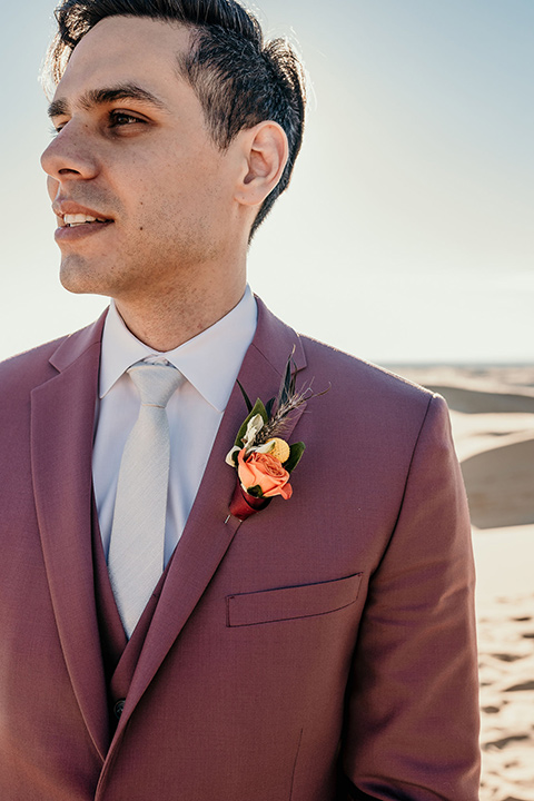  the groom in a rose pink suit with a white long tie 