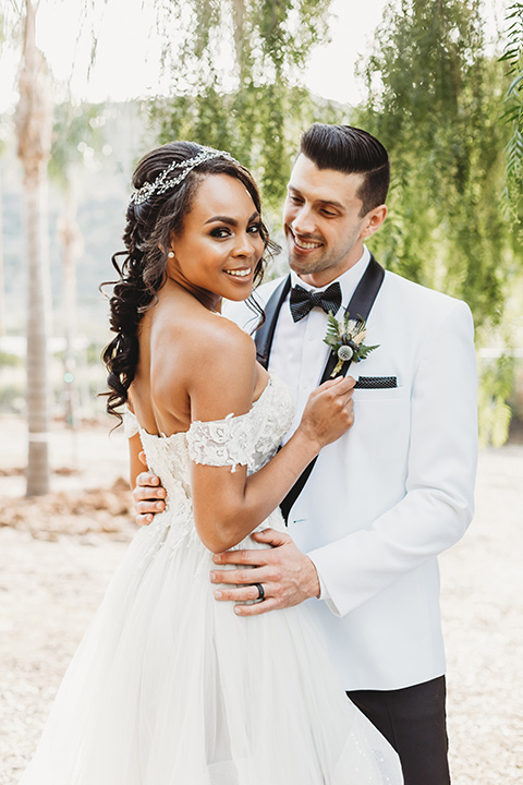  bridal hair with a braid and headpiece in a lace ballgown with an off the shoulder detail and the groom in a white with black shawl lapel tuxedo – bride walking down the aisle