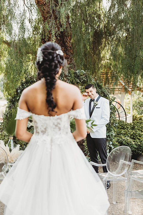  bridal hair with a braid and headpiece in a lace ballgown with an off the shoulder detail and the groom in a white with black shawl lapel tuxedo – bride walking down the aisle