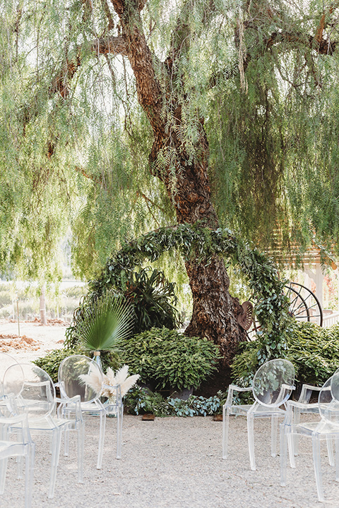  ceremony details with a green arch and acrylic chairs