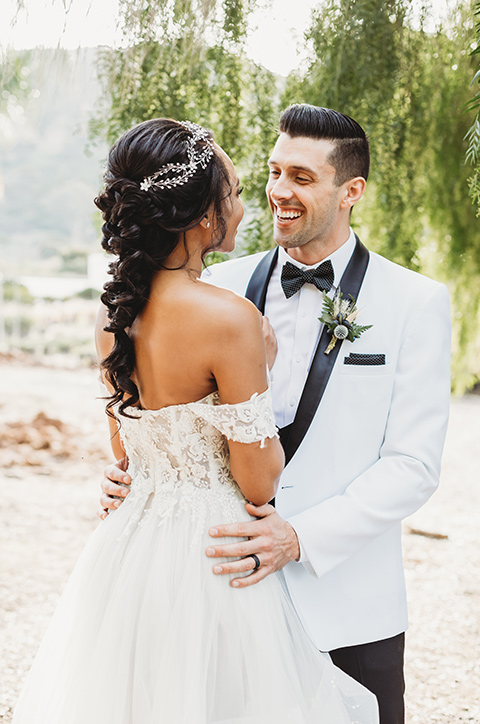  bride in a lace ballgown with off the shoulder neckline and groom in a white with a black shawl lapel tuxedo