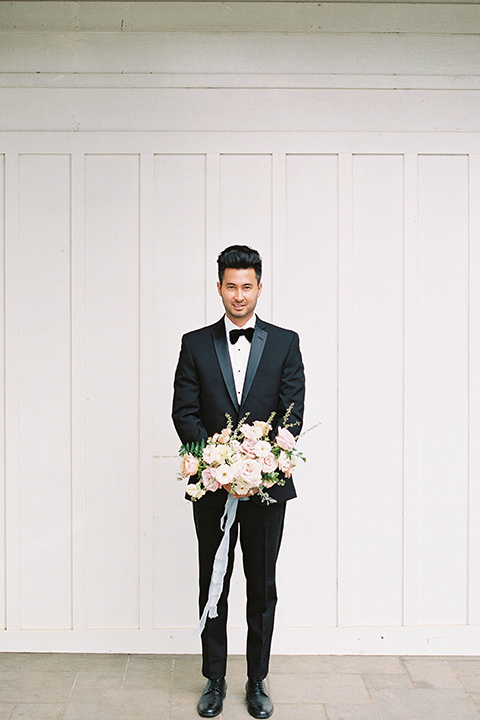  the groom in a black notch lapel tuxedo with bow tie 