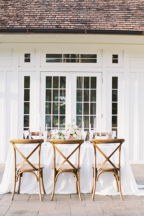  reception table set up with wooden farmhouse chairs and white table linens 