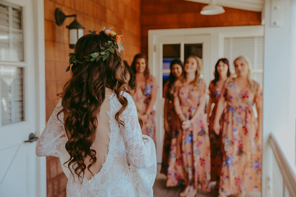  bride in a lace bohemian gown with tulip sleeves and a braided crown, and the bridesmaids in pink floral gowns 