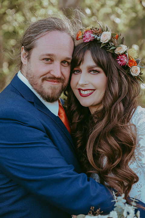  bride in a lace bohemian gown with tulip sleeves and a braided crown, the groom in a cobalt blue suit for purchase with a burnt orange tie 