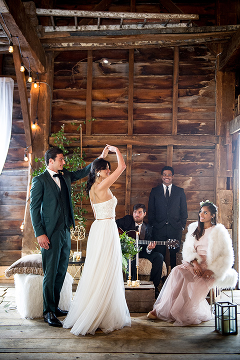  bride in a white ballgown with her hair in a loose brain and garden bouquet the groom in a green suit dancing with a live band