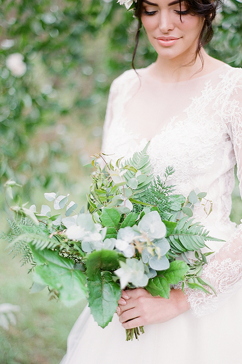  bride in a lace ballgown with long sleeves and a green and white bouquet