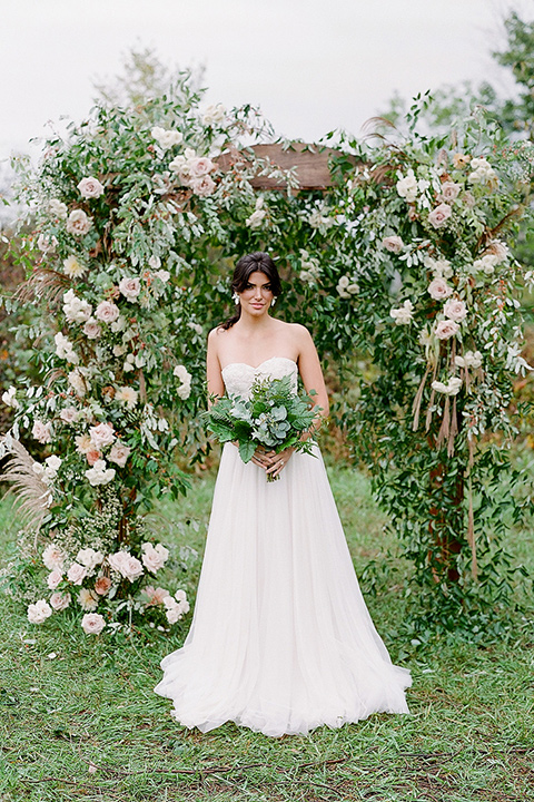  bride in a white ballgown with her hair in a loose brain and garden bouquet