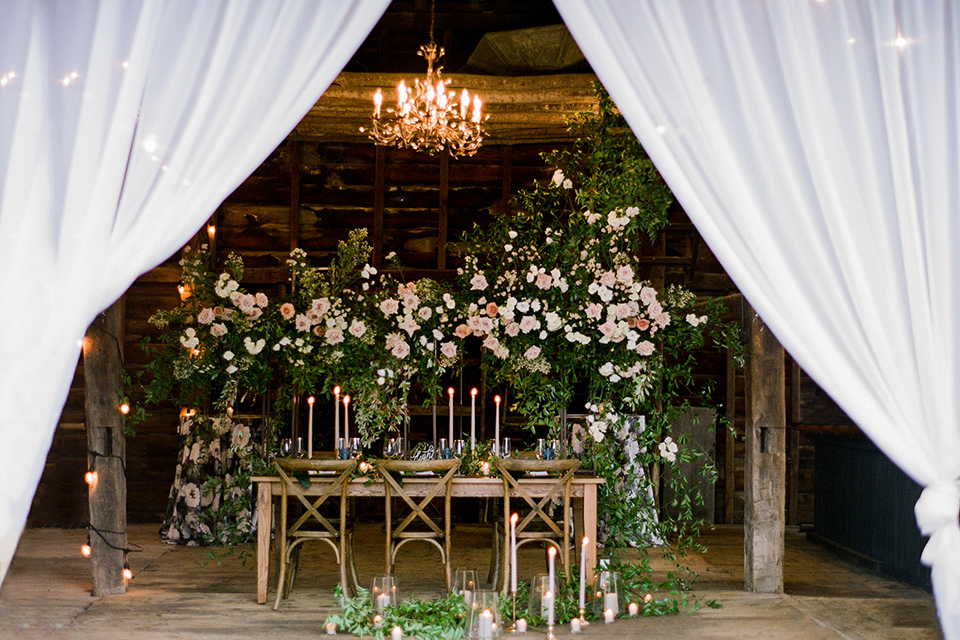  wooden table with green and rose flowers and white flowing linens