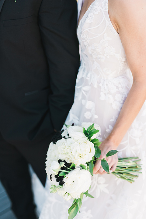 bride in a white gown with a deep v neckline and thin straps and the groom in a black tuxedo