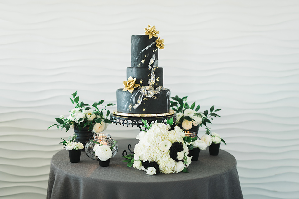 a cake with black fondant and silver and gold detailing