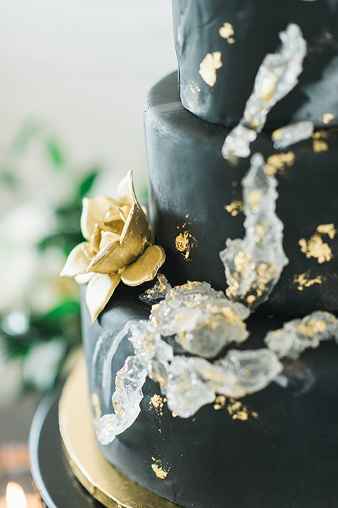 black fondant on a cake with silver and gold flakes