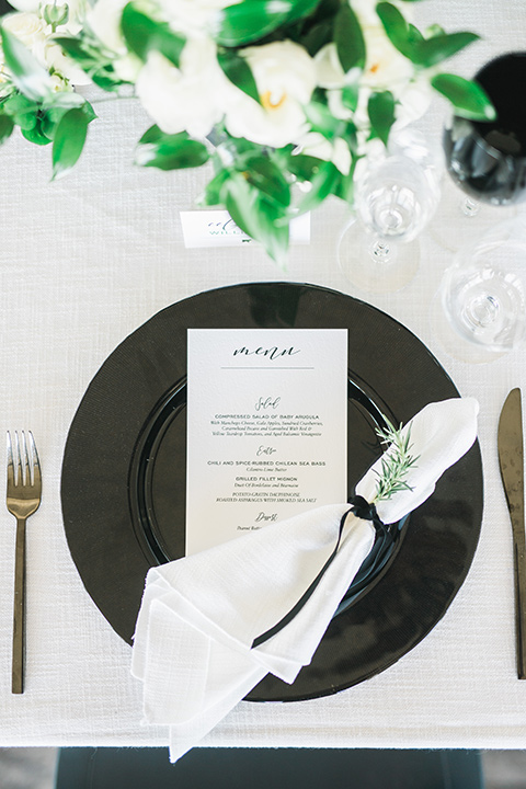 black plates on a white table linen with gold flatware