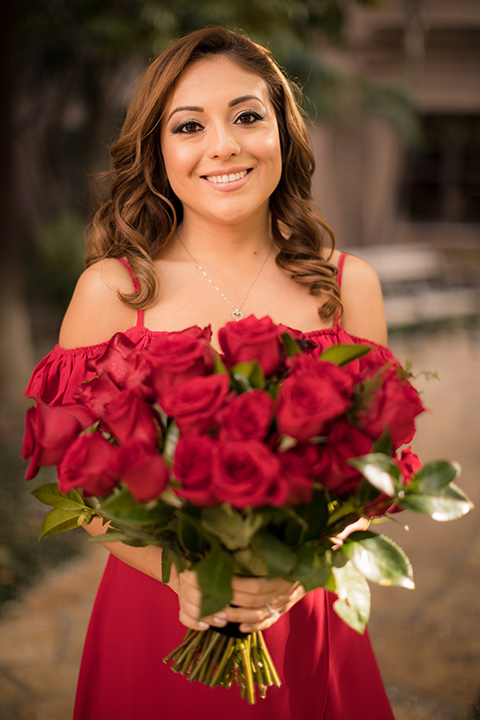  girl in a long red dress with an off the shoulder detail and roses