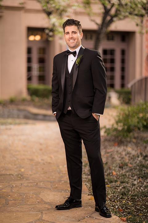  man in a black tuxedo with a shawl lapel tuxedo and a black bow tie