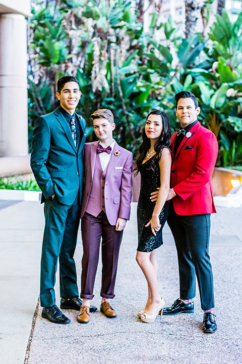 group of friends going to prom with each other and one female model wearing a rose colored suit coat with burgundy pants and brown shoes 