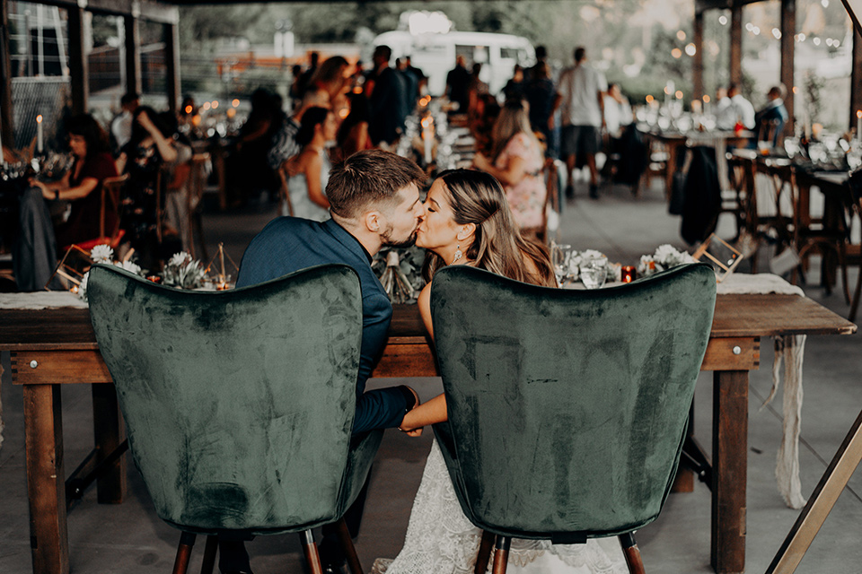  groom and groomsmen in dark blue suits with bow ties, bridesmaids in soft pastel colors in different patterns and designs, the bride in a flowing white gown with an off the shoulder detail 