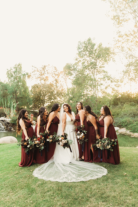  ride in a white ballgown with a plunging neckline and long veil and the bridesmaids in burgundy gowns 
