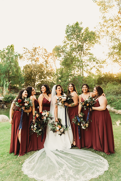  ride in a white ballgown with a plunging neckline and long veil and the bridesmaids in burgundy gowns