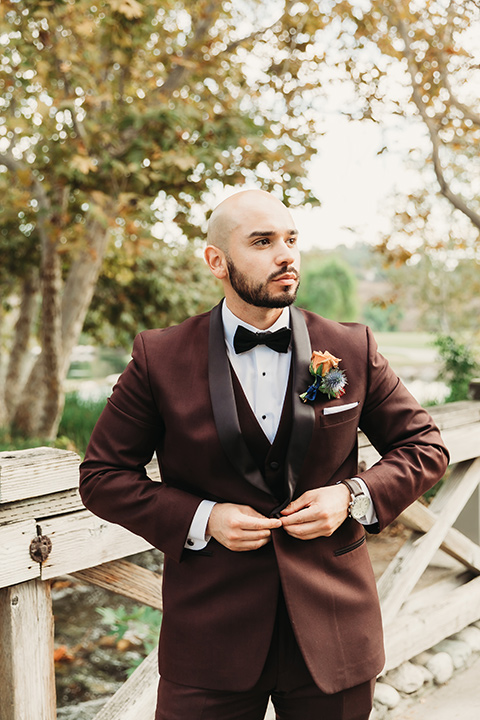  the groom in a burgundy tuxedo with a black shawl lapel