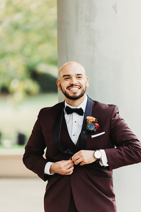  the groom in a burgundy tuxedo with a black shawl lapel 