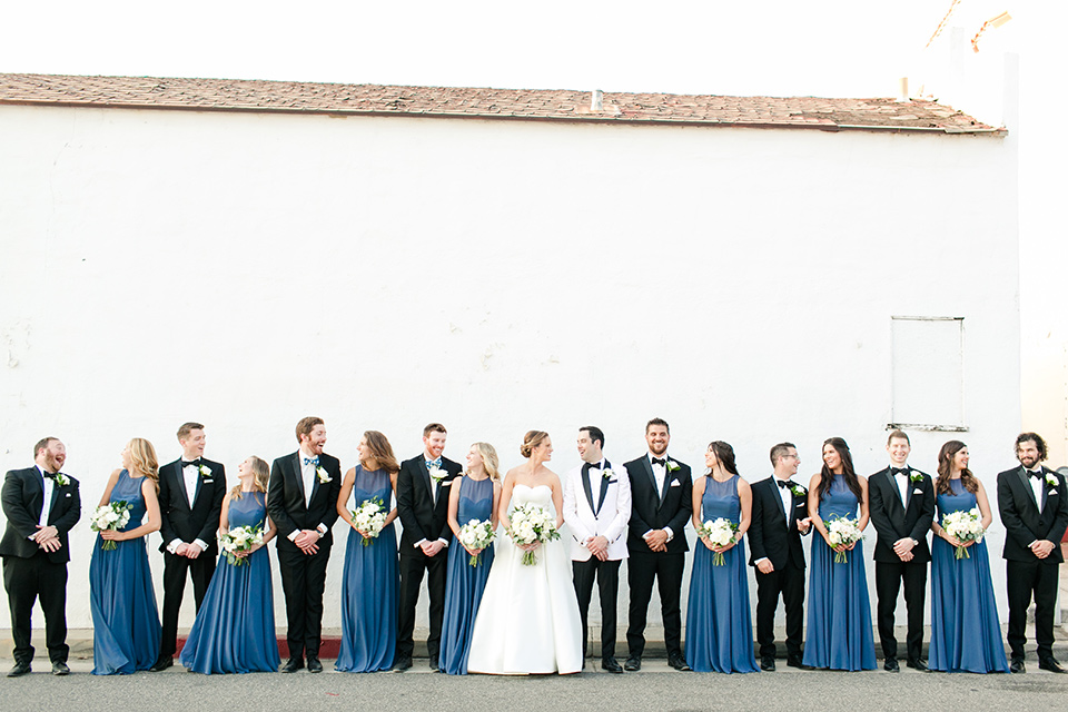  bride in a ballgown with a sweetheart neckline and the groom in a black tuxedo, the bridesmaids wore deep teal blue gowns and the groomsmen in a black tuxedo with blue bow ties 
