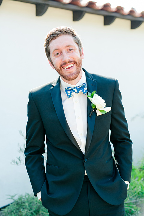  bride in a ballgown with a sweetheart neckline and bridesmaids in deep teal gowns and the bridesman in a black tux with blue bow tie 