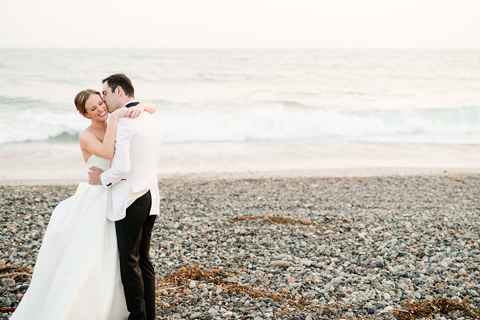  bride in a ballgown with a sweetheart neckline and the groom in a black tuxedo, the bridesmaids wore deep teal blue gowns and the groomsmen in a black tuxedo with blue bow ties 