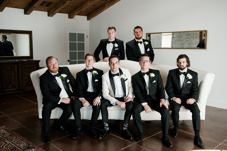  bride in a ballgown with a sweetheart neckline and the groom in a black tuxedo, the bridesmaids wore deep teal blue gowns and the groomsmen in a black tuxedo with blue bow ties 