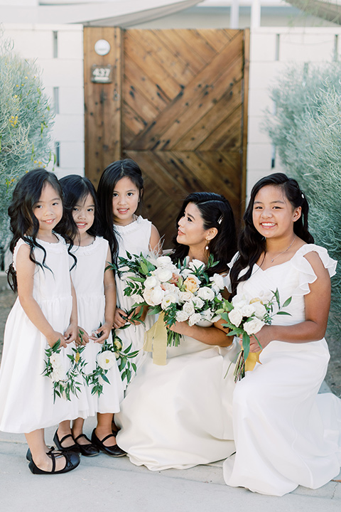  bride in a white modern ballgown with pockets and a low cut neckline and bridesmaids in neutral gowns