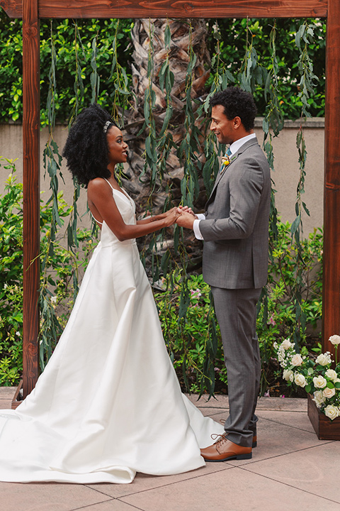  bride in a white lace formfitting gown with a V-neckline, and the groom in a café brown suit a dusty teal long tie 