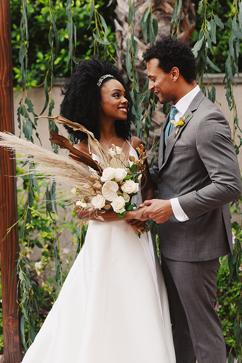  bride in a white lace formfitting gown with a V-neckline, and the groom in a café brown suit a dusty teal long tie 