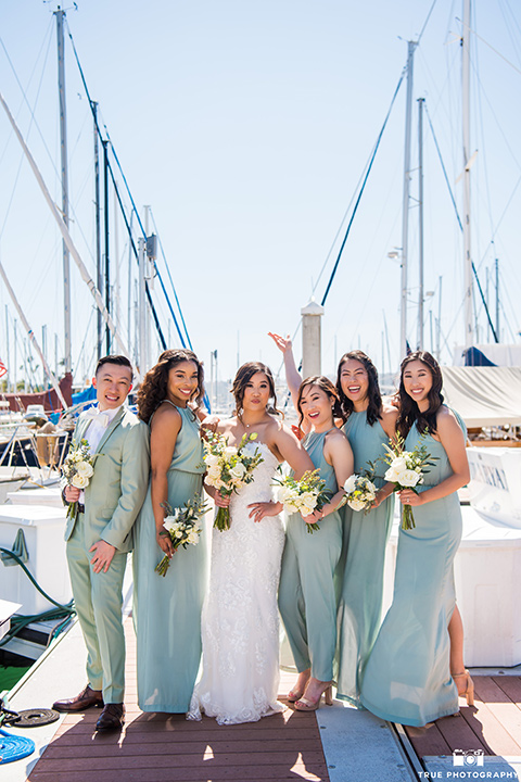 bride in a white lace form fitting gown with a strapless sweetheart neckline, the the bridesmaids in mint blue gowns and the bridesman in a mint suit to match the girls’ gown 