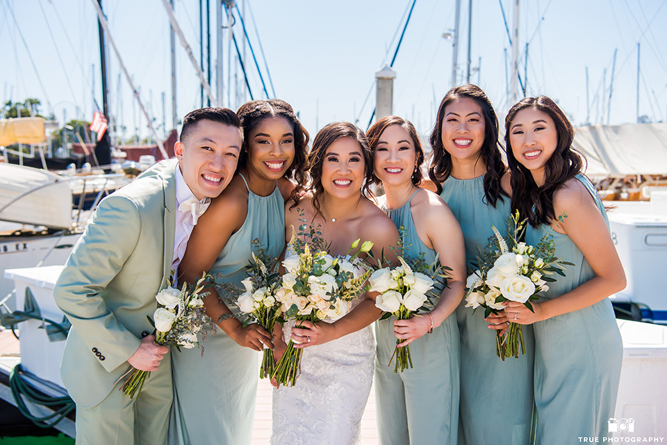  bride in a white lace form fitting gown with a strapless sweetheart neckline, the the bridesmaids in mint blue gowns and the bridesman in a mint suit to match the girls’ gown