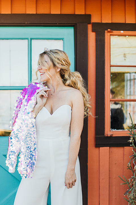  bride was in a white strapless jumpsuit with a colorful jacket and hair in a ponytail 