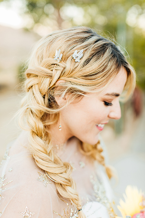  bride was in a white strapless jumpsuit with a colorful jacket and hair in a ponytail 