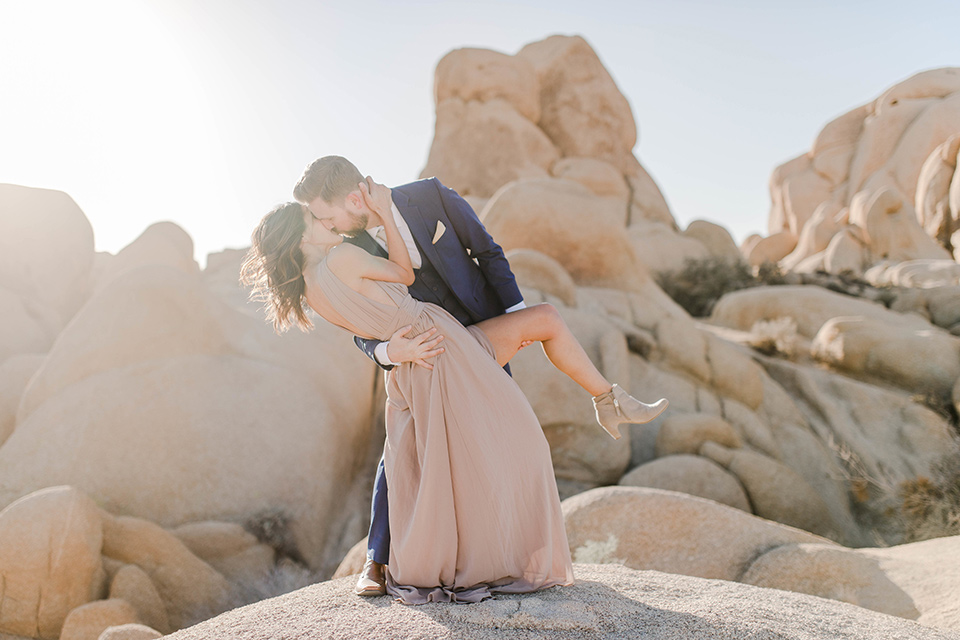  bride in a taupe gown with ankle boots and straps, the groom in a cobalt blue suit with a neutral colored tie dancing