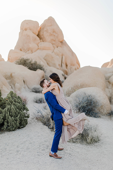 bride in a taupe maxi gown with straps and her hair down, the groom in a cobalt blue suit with a neutral long tie