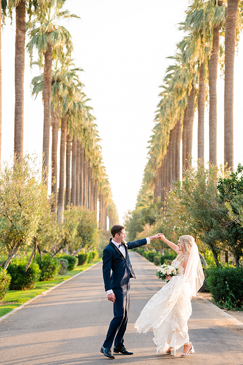  bride in a formfitting gown with thin straps and lace details, the groom in a navy tuxedo 