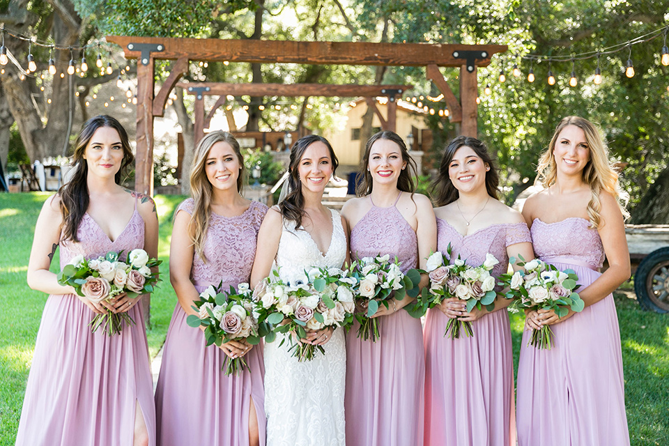  bride in a lace form-fitting gown with straps the bridesmaids in lavender gowns 