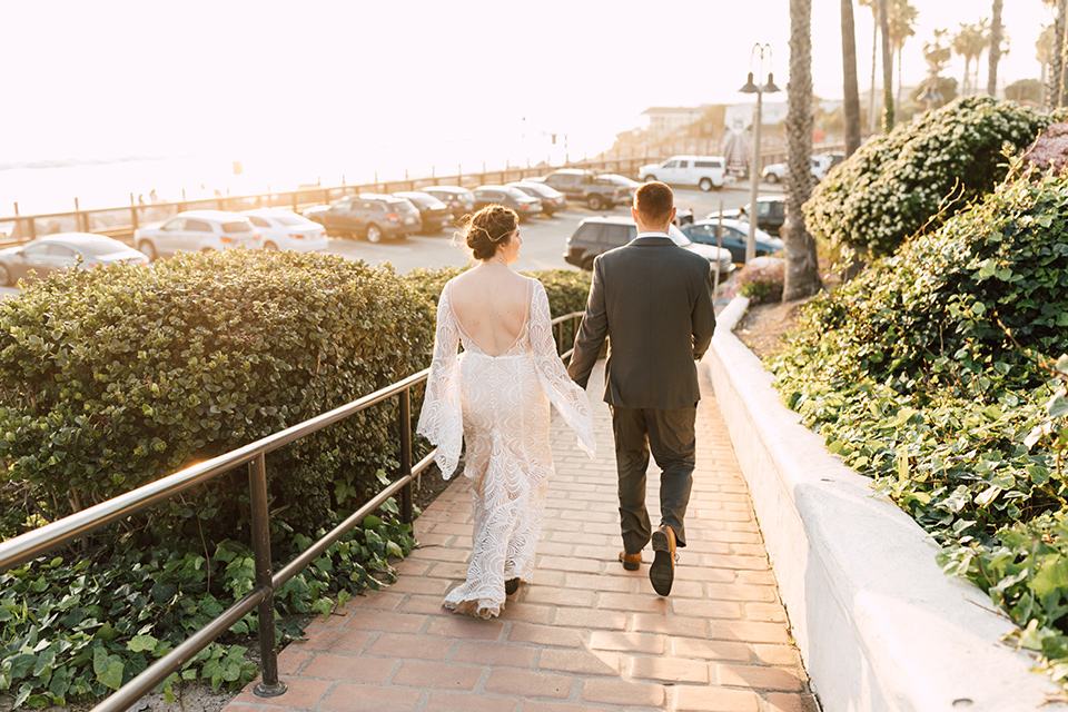bride in a lace bohemian gown with a high neckline and flutter sleeves, the groom was in grey retail suit with a blue long tie, walking down stairs