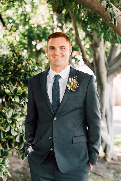 groom in a grey notch lapel suit with a blue long tie and brown shoes