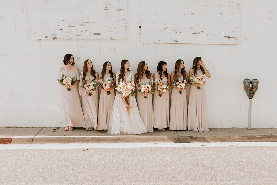  bride in a flowing ballgown and the bridesmaids in neutral colors