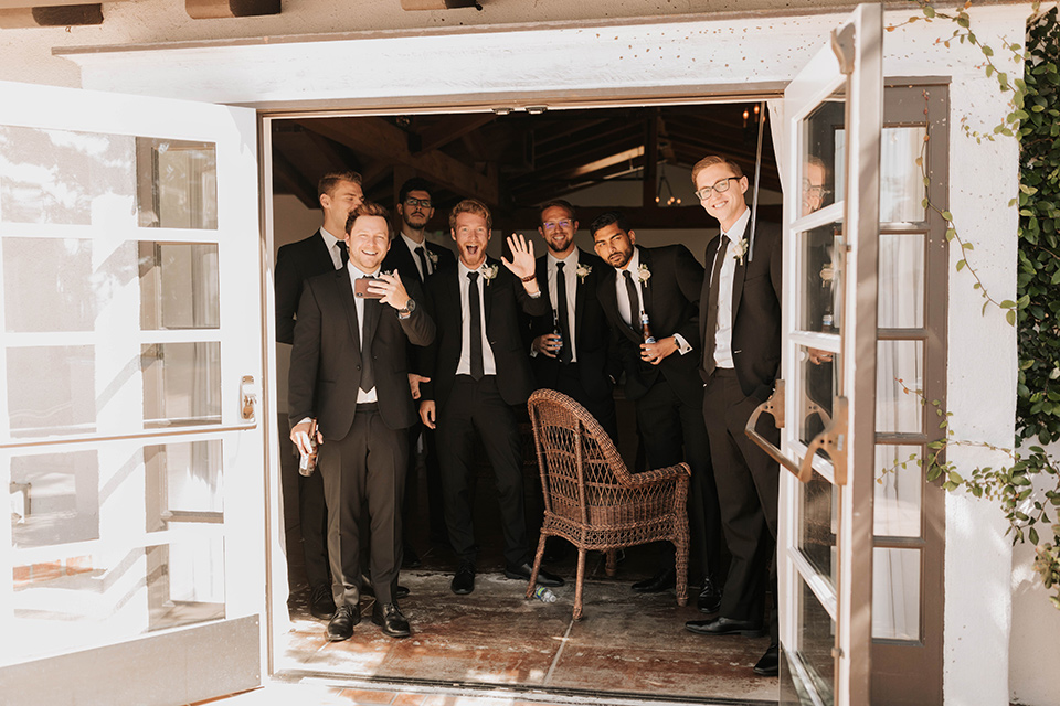  bride in a flowing ballgown and the groom in a black suit, the bridesmaids in neutral colors and the groomsmen in black suits and long ties 