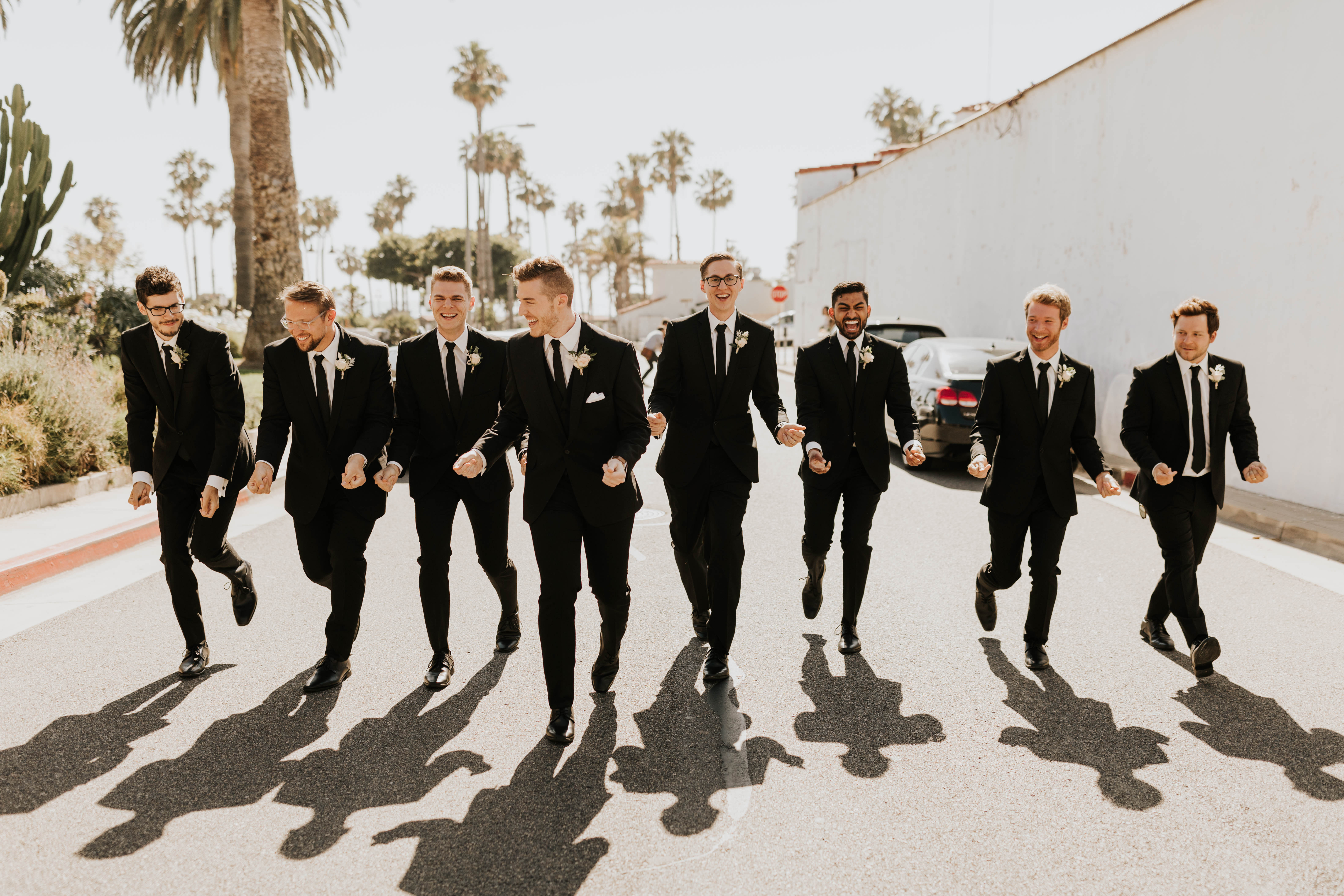  bride in a flowing ballgown and the groom in a black suit, the bridesmaids in neutral colors and the groomsmen in black suits and long ties 