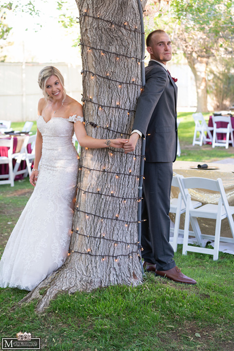  bride in a white lace gown with an off the shoulder detail and long veil and the groom in a dark grey suit 