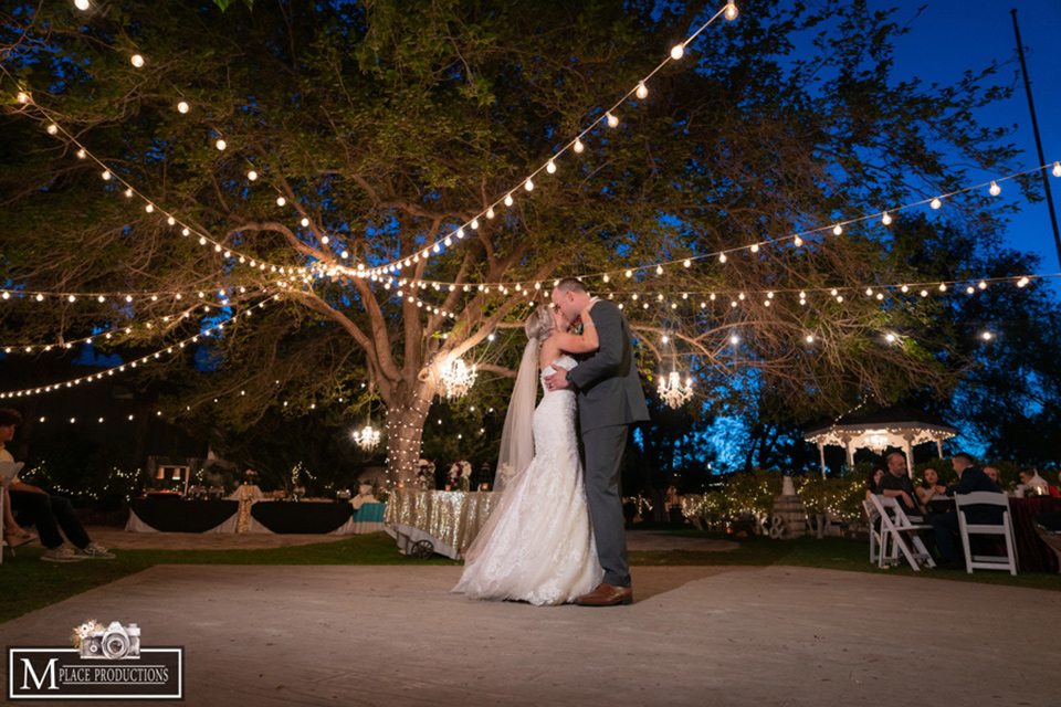  bride in a white lace gown with an off the shoulder detail and long veil and the groom in a dark grey suit first dance