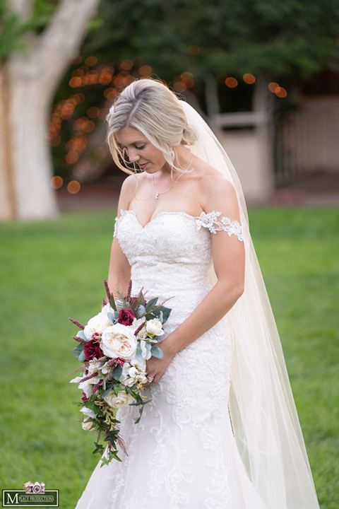  bride in a white lace gown with an off the shoulder detail and long