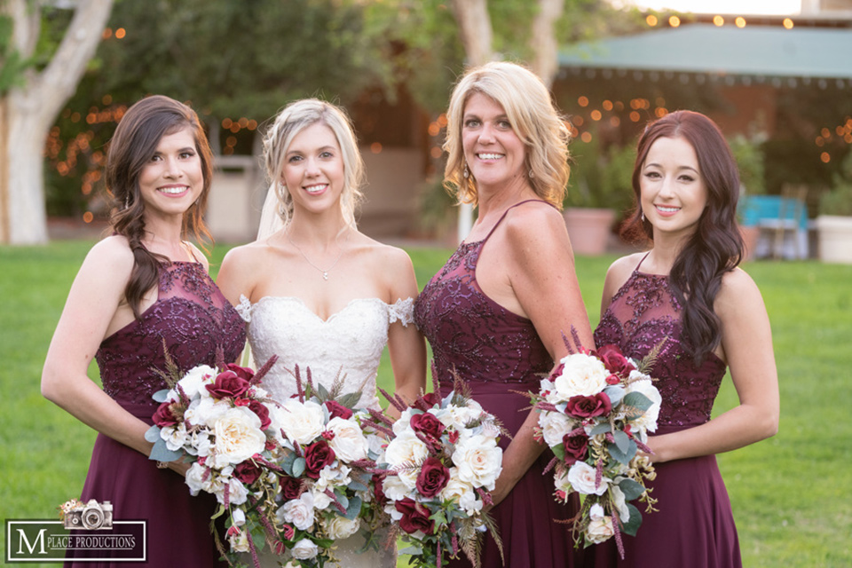  bride in a white lace gown with an off the shoulder detail and long veil and the bridesmaids in burgundy long dresses