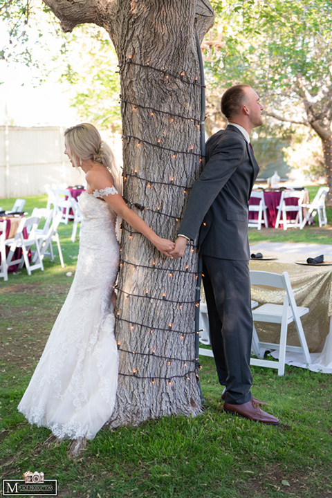  bride in a white lace gown with an off the shoulder detail and long veil and the groom in a dark grey suit